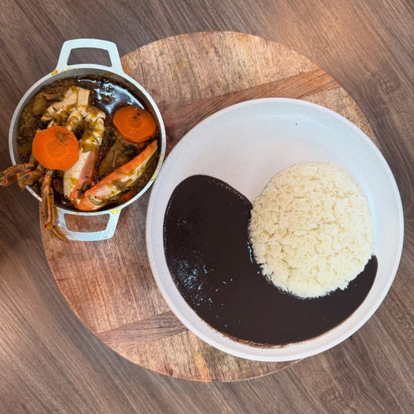 Haitian crab stew with carrots in a pot, served with white rice and black bean sauce.