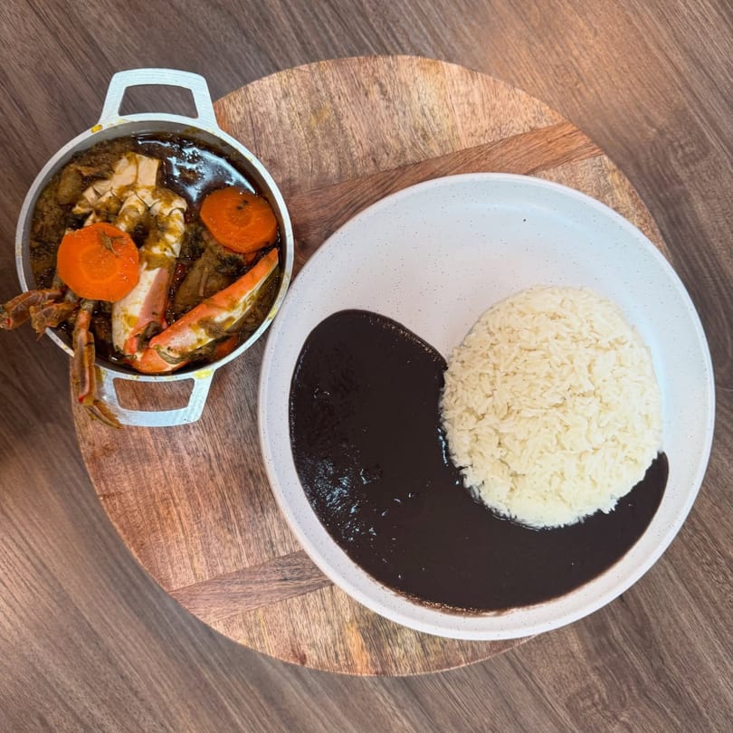 Haitian crab stew with carrots in a pot, served with white rice and black bean sauce.
